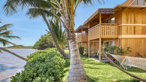 A wooden building with a balcony, surrounded by palm trees and a hammock. - Vacasa at Hotel Molokai (Kaunakakai)
