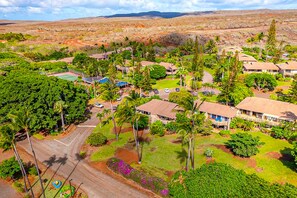 An aerial view of a resort with multiple bungalow-style buildings, a tennis court, and lush greenery. - Ke Nani Kai (Maunaloa)