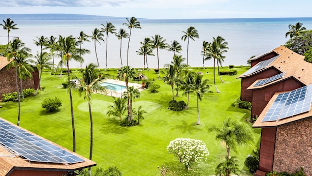 A resort with a pool, palm trees, and a view of the ocean. - Molokai Shores (Kaunakakai)
