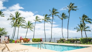 A swimming pool with a no diving sign, surrounded by palm trees and a clear sky. - Molokai Shores (Kaunakakai)