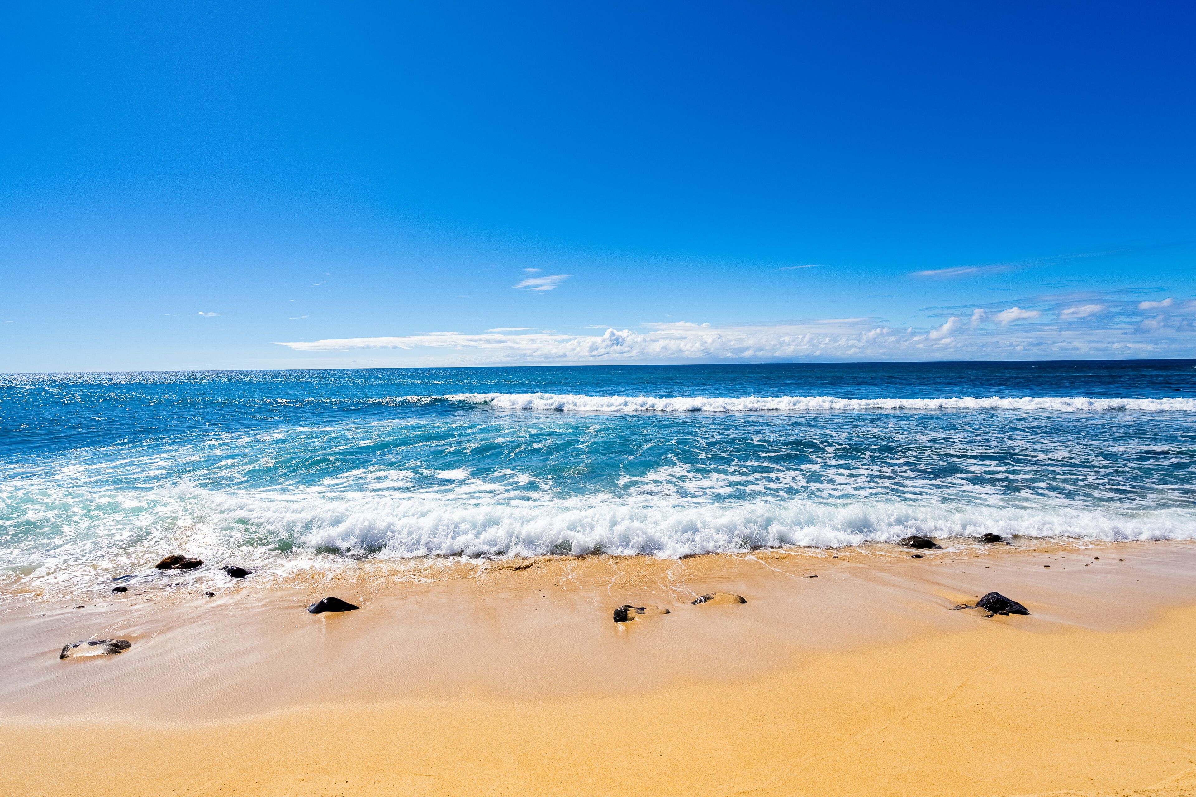 A beach with clear blue water and a sandy shore.