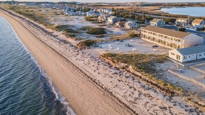 Un hôtel situé sur la côte, avec vue sur la plage, comprenant plusieurs chambres et un espace de stationnement.