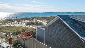 Une vue sur la côte, avec une plage, une clôture en bois et un bâtiment doté d’un toit en pente.