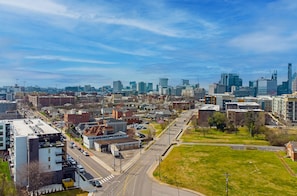 An urban cityscape with modern buildings, a wide road, and a grassy area.