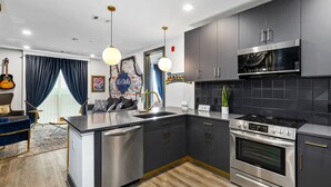 A modern kitchen with stainless steel appliances, dark cabinetry, and a central island. - Muse Nashville (Nashville)