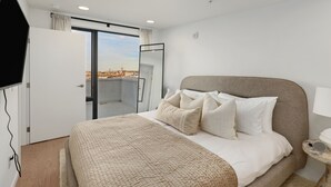 A modern hotel room with a large bed, a flat-screen TV mounted on the wall, and a balcony with a city view. - Eve Nashville  (Nashville)