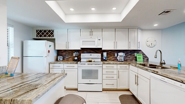 A modern kitchen with white cabinets, a built-in oven, a microwave, and a coffee maker. - Suntide II Condominiums (South Padre Island)