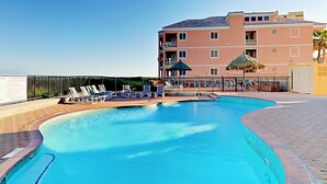 A swimming pool with lounge chairs and a building in the background. - Suntide II Condominiums (South Padre Island)