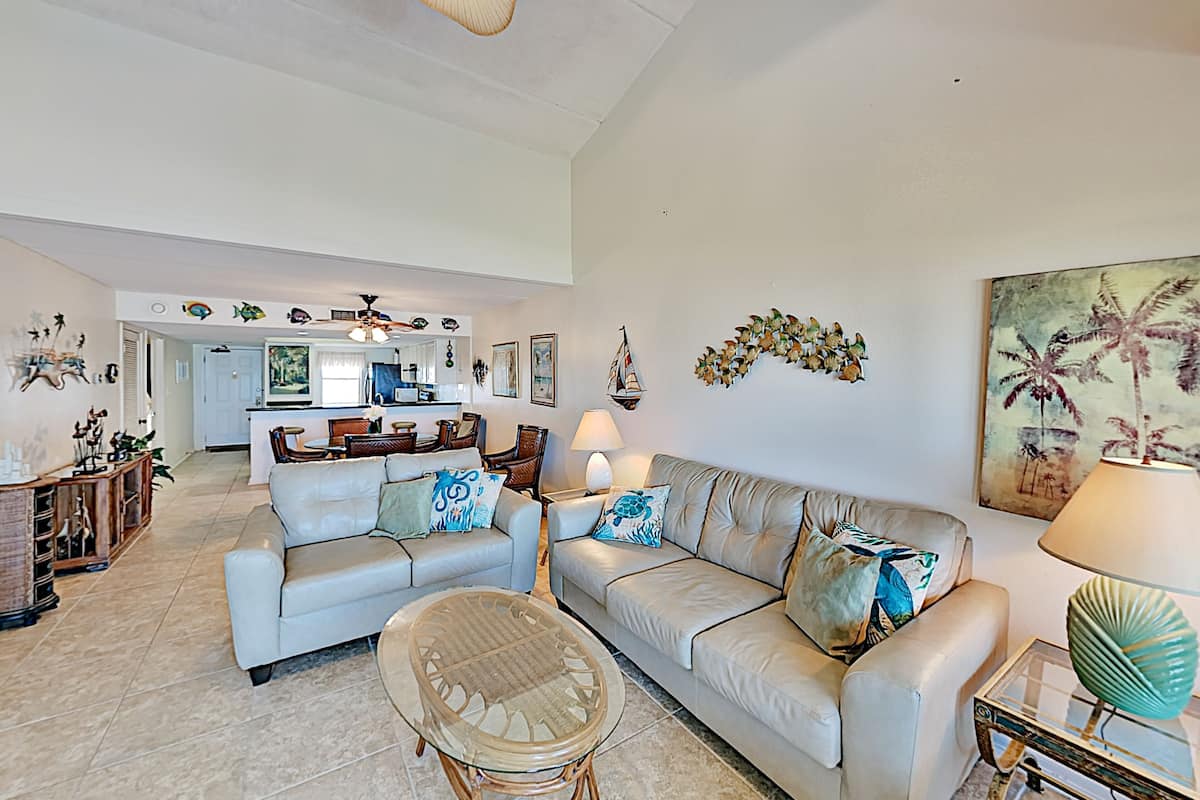 A spacious living area with two sofas, a coffee table, and a dining area in the background.
