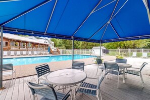 A covered outdoor area with a pool, lounge chairs, and tables.