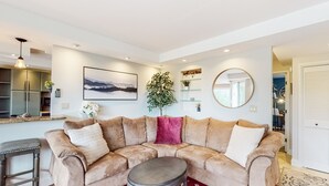 A modern living room with a beige sectional sofa, a round coffee table, and a red patterned rug. - Bridges Resort (Warren)