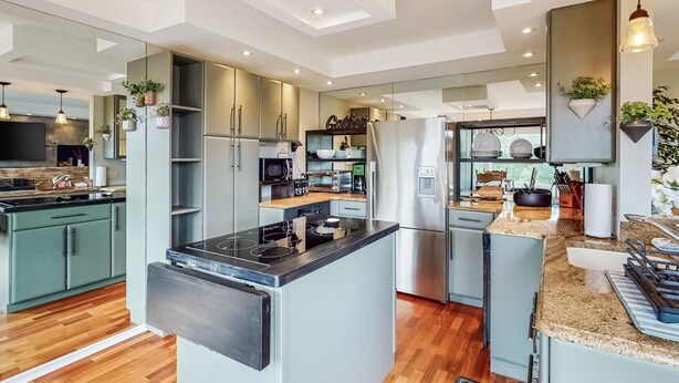 A modern kitchen with a central island, built-in appliances, and a dining area with a view. - Bridges Resort (Warren)