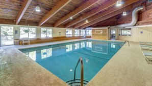 An indoor swimming pool with wooden beams, clear windows, and a tiled floor. - Bridges Resort (Warren)