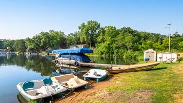 A lakeside dock with several boats, a covered area, and a small building.