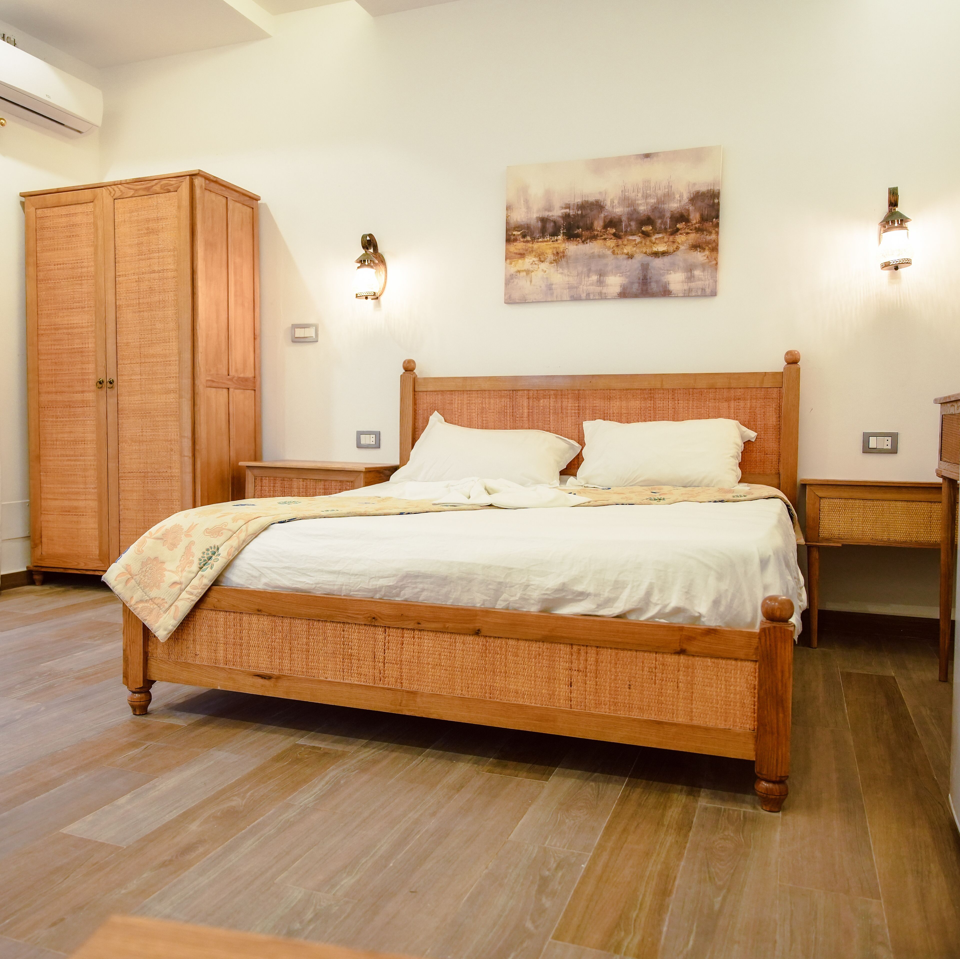 Un dormitorio con cama de madera, mesitas de noche, un armario y un cuadro en la pared.