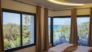 A bedroom with a large bed, a view of the ocean, and a balcony with a chair. -  Dar Oguz (Hammam Al Agzaz)