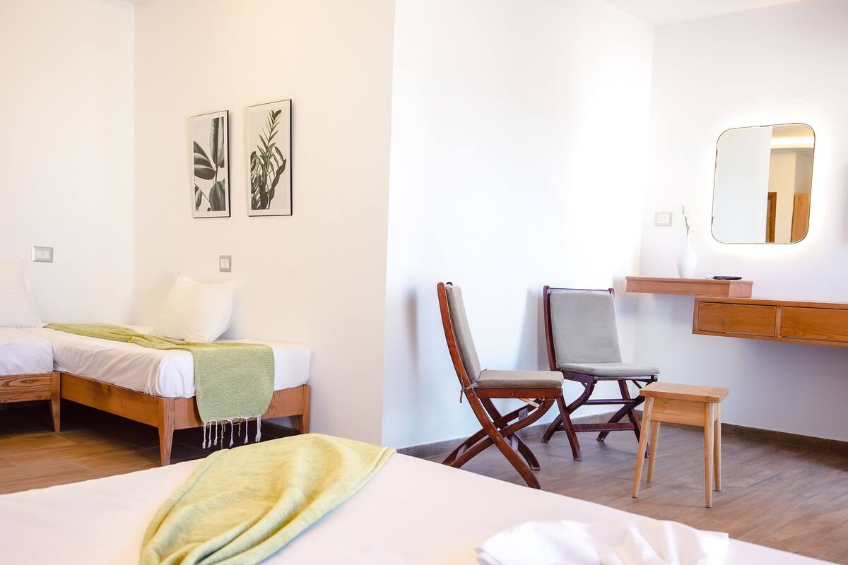 Een hotelkamer met een bed, een stoel, een bureau en een spiegel.