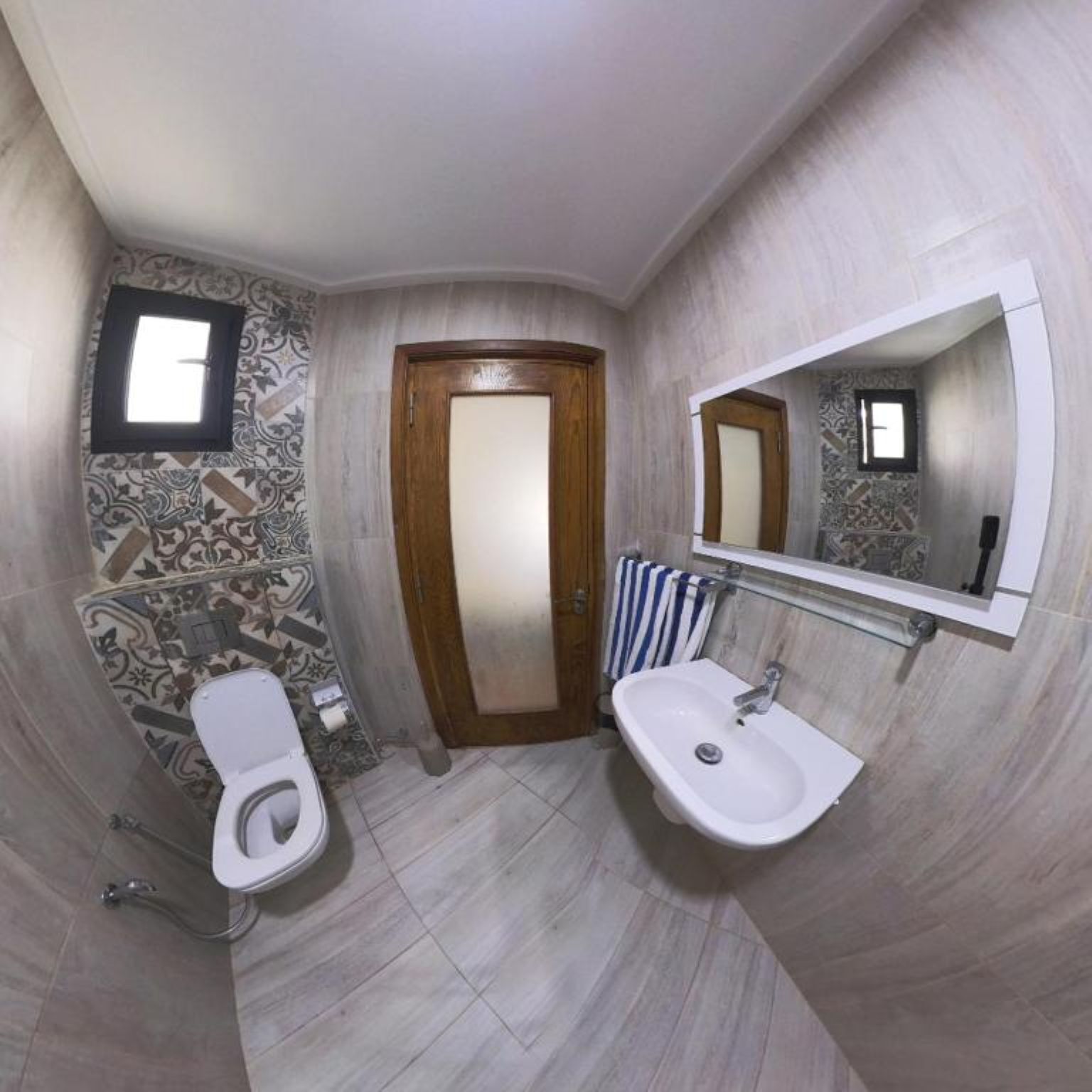 A bathroom with a toilet, sink, and a mirror.