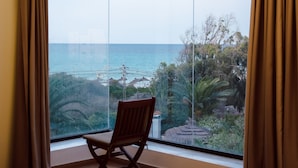 A room with a large window offering a view of the sea and greenery. -  Dar Oguz (Hammam Al Agzaz)