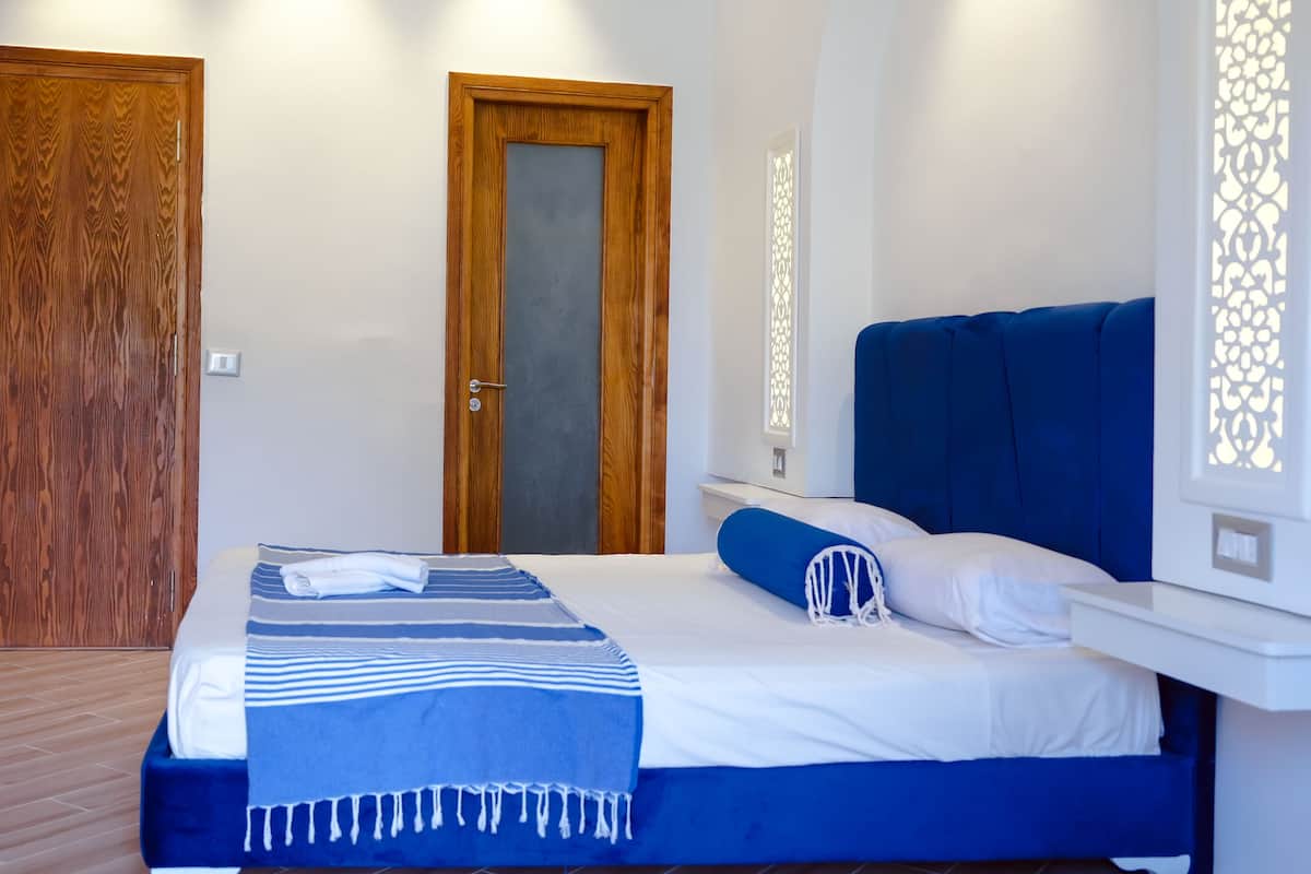 Een slaapkamer met een bed, een houten deur en een witte muur met een decoratief paneel.