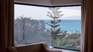 A room with a large window offering a view of the sea and trees. -  Dar Oguz (Hammam Al Agzaz)