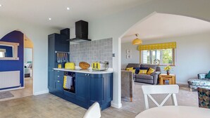 Una cocina moderna con armarios azules, horno empotrado y un tostador amarillo.