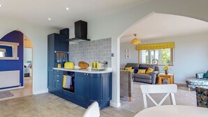 Una cocina moderna con armarios azules, horno empotrado y un tostador amarillo.
