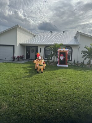 A house with a metal roof, a garage, and a front yard with grass and a Santa Claus decoration.