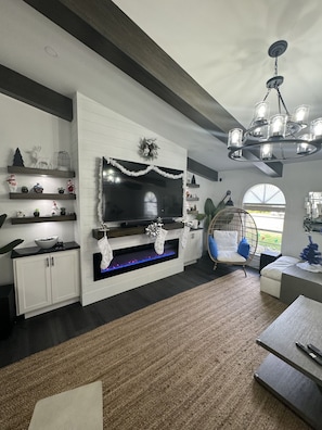 A modern living room with a fireplace, a television, and a hanging chair. - The Board Room - A Unique Experience (Bonita Springs)