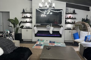 A modern living room with a fireplace, a sofa, a coffee table, and decorative shelves. - The Board Room - A Unique Experience (Bonita Springs)