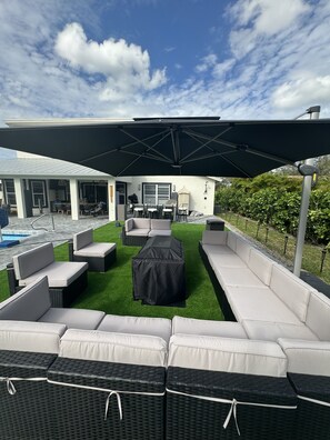 A covered outdoor seating area with a pool in the background. - JUST IN TIME FOR SEASON! (Bonita Springs)