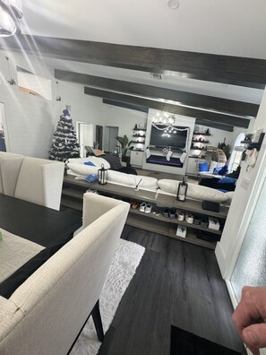 Una sala moderna con un sofá, una mesa de comedor y un televisor montado en la pared.