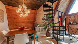 A wooden interior with a dining area, a spiral staircase, and a chandelier. - Cozy A-Frame Cabin | Lake Access + Fire Pit (Guntersville)