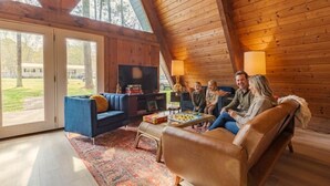 A cozy room with a TV, sofa, and coffee table. - Cozy A-Frame Cabin | Lake Access + Fire Pit (Guntersville)
