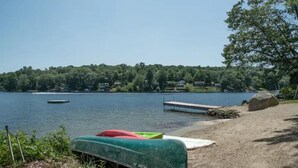 Vista de un lago con un muelle, un bote cubierto y una playa de arena.