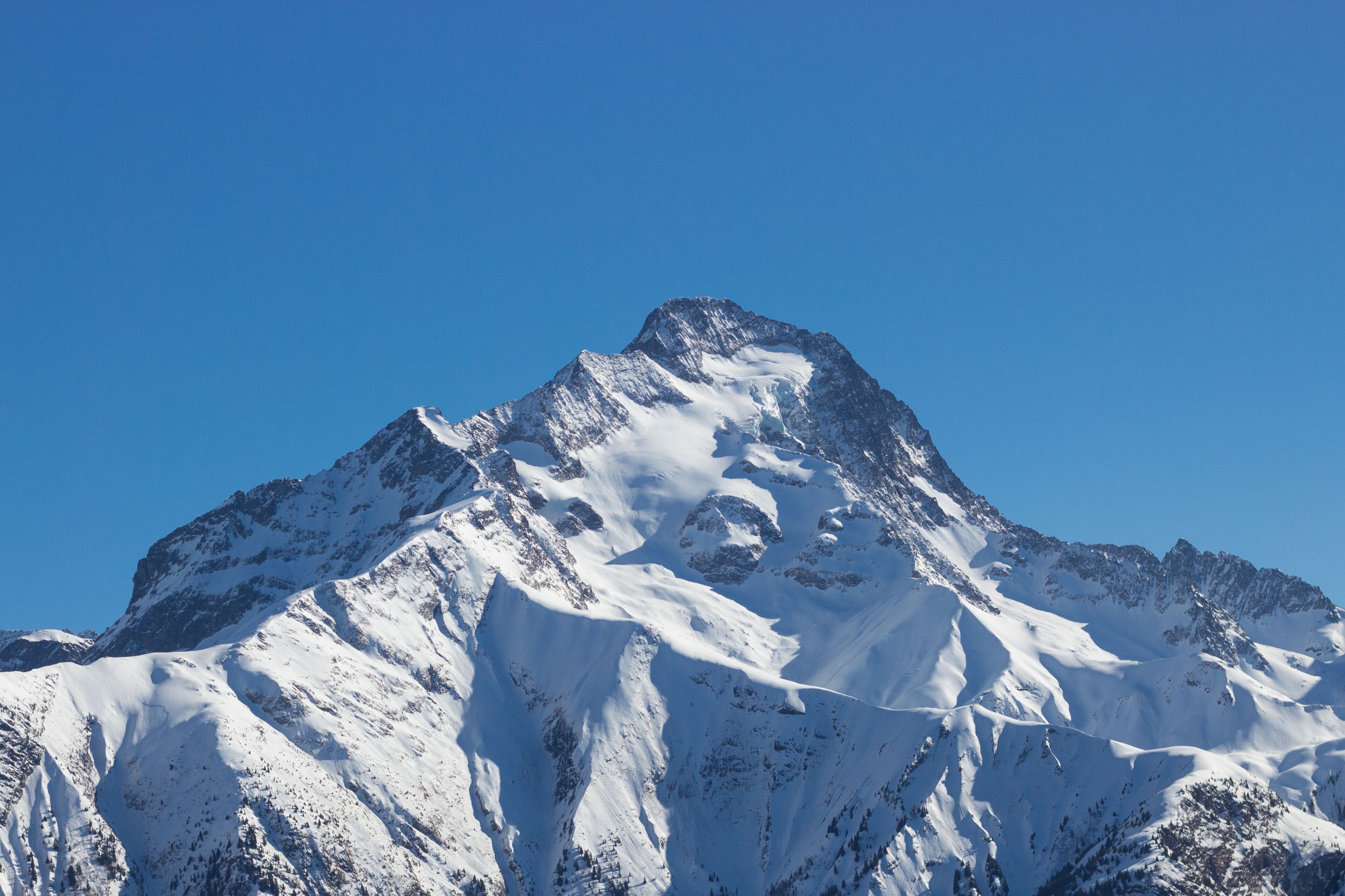 A snow-covered mountain peak with a clear blue sky.