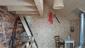 A rustic wooden interior with a lofted sleeping area, a dining table, and a chimney. - The “Cabane des Deux Soeurs”  (Le Bourg-d'Oisans)