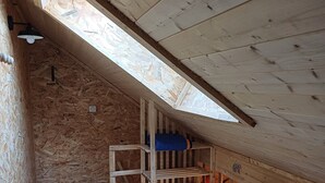 A wooden interior with a sloped ceiling, a bunk bed, a small table, and a cowhide rug. - The “Cabane des Deux Soeurs”  (Le Bourg-d'Oisans)