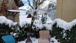 A snow-covered outdoor area with a stone building, a wooden structure, and two metal chairs. - The “Cabane des Deux Soeurs”  (Le Bourg-d'Oisans)