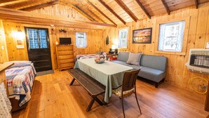 A cozy cabin interior with a wooden interior, a dining table, a sofa, and a bench.