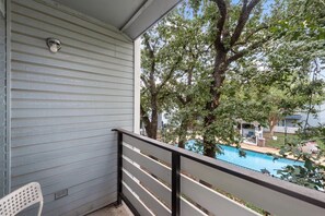 A balcony with a view of a swimming pool and trees.