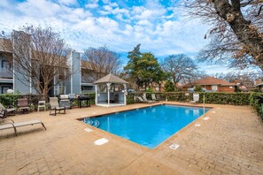 A rectangular swimming pool with a gazebo and lounge chairs in a residential area.