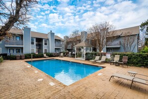 A swimming pool with lounge chairs, a gazebo, and a brick patio.