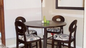 Un comedor con una mesa redonda, cuatro sillas, una lámpara de pie y un espejo en la pared.