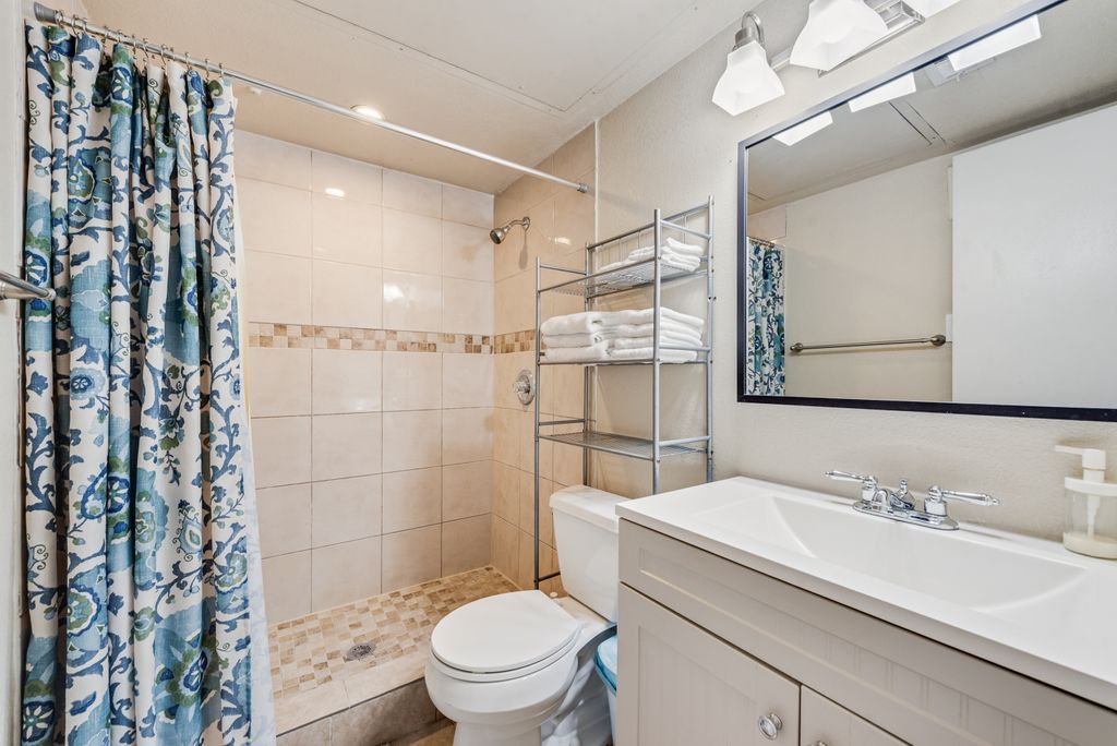 Un bagno con doccia, toilette e lavandino con specchio.
