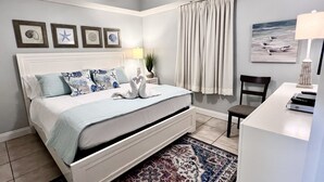 A bedroom with a bed, a desk, a chair, a rug, and wall art.