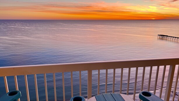A balcony with a view of the ocean and a pier.