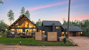 Une maison en rondins moderne dotée d’une grande terrasse, d’un porche couvert et d’un garage.