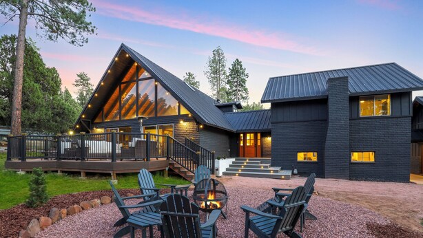 Une maison moderne dotée d’une terrasse, d’un espace salon extérieur et d’un foyer.