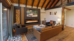 Un salon spacieux doté d’une cheminée, de sièges confortables et d’un ventilateur de plafond.